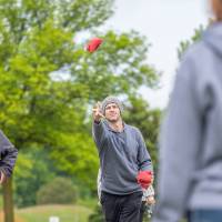 A staff member throws a red cornhole bag